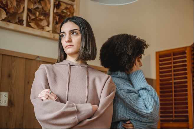 Two women facing away from each other experiencing a conflict