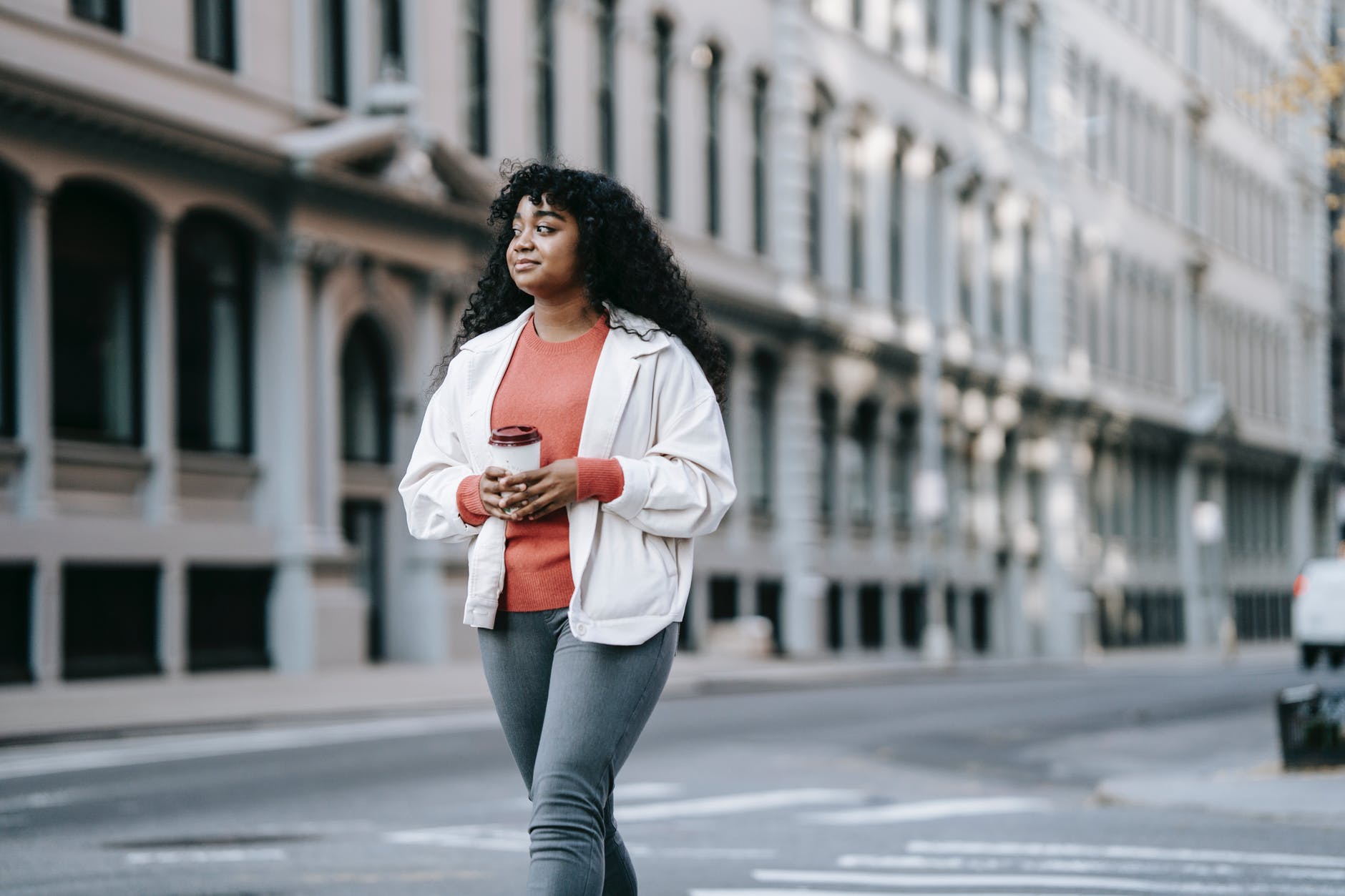 african american female on city street strolling with takeaway drink